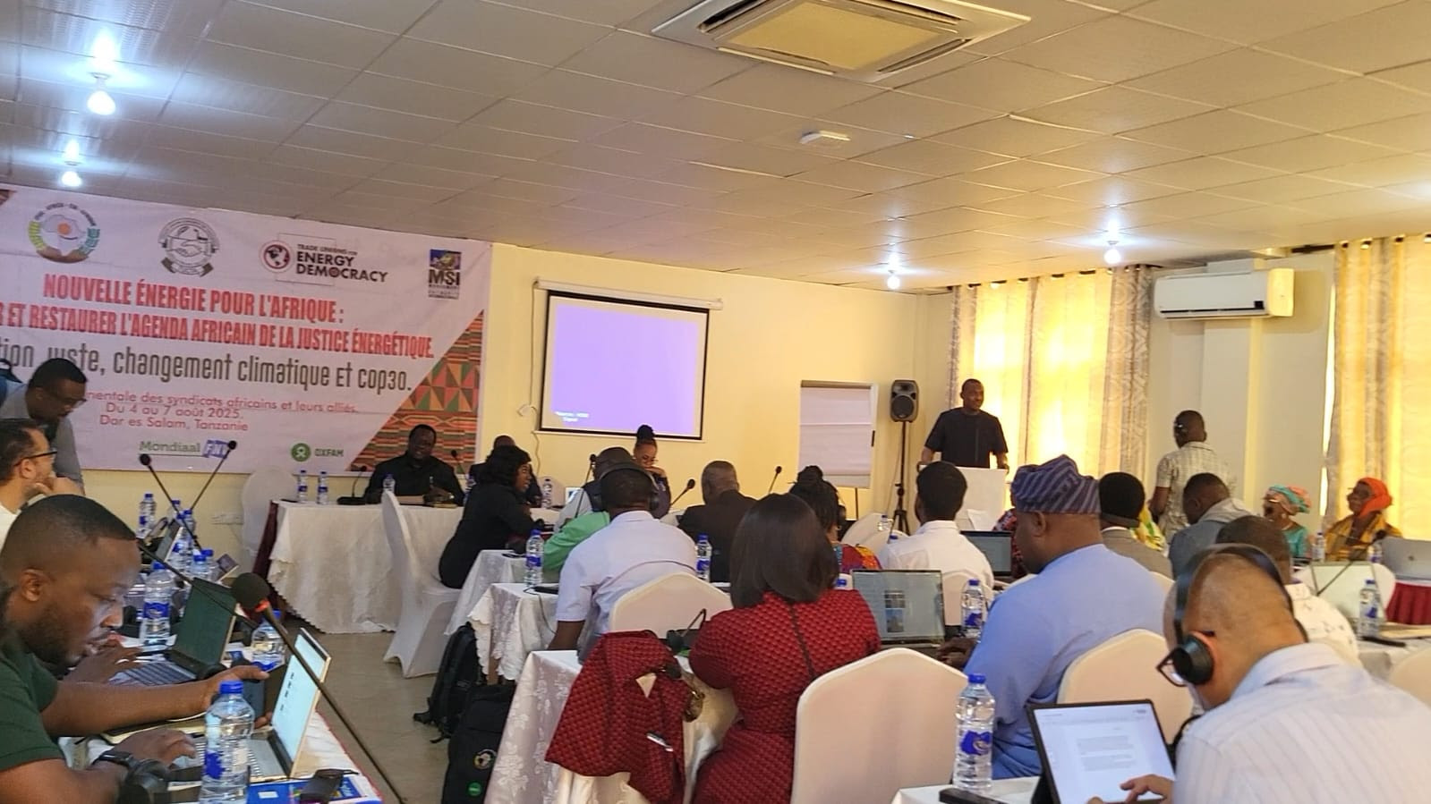 TUED Africa regional meeting in Dar es Salaam — delegates in session before a banner for energy justice and COP30